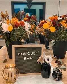 a table topped with vases filled with flowers next to a sign that says bouquet bar