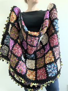 a woman wearing a black crocheted shawl with multicolored flowers on it