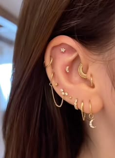 a woman wearing gold ear cuffs with stars and crescents