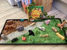 a tray filled with lots of different types of toy animals and plants on top of a wooden floor