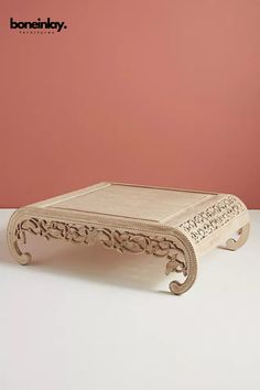 a wooden coffee table sitting on top of a white counter next to a pink wall