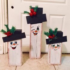 three wooden boxes with faces painted on them and christmas decorations in the shape of snowmen