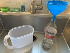 a bottle of water sitting on top of a kitchen sink next to a strainer