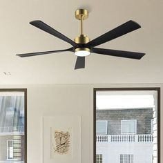 the ceiling fan is hanging from the ceiling in the living room with two large windows