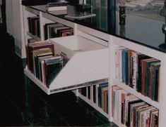 a book shelf filled with lots of books next to a counter topped with vases