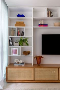 an entertainment center with bookshelves, vases and a flat screen tv mounted on the wall