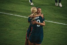 two female soccer players hugging each other on the field