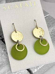 "The round link is plated with glossy 18K gold . The finish is glossy because it is rack plated. This means that the pieces are hand hung so they receive the optimal amount of coverage. Hanging from the link is a sea glass round drop with 18K gold barrel plated rings. The sea glass comes in five different colors as follows: 1) Lime Green 2) Turquoise 3) Teal 4) Mint Green 5) Navy The earrings are lead safe. The ear wires are 16 K gold plated with rubber back stoppers. The full length of the earr Modern Green Round Earrings, Elegant Green Circular Earrings, Gold Round Disc Earrings, Gold Round Disc Earrings For Pierced Ears, Mint Green Earrings, Stained Glass Earrings, Silver Gold Earrings, Mint Earrings, Patina Earrings