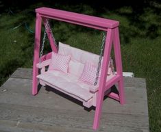 a pink wooden swing with pillows on it