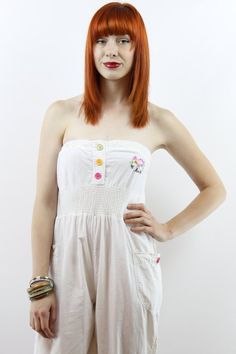 The item: Vintage nineties STRAPLESS WHITE JUMPSUIT. Embroidered emblem at chest. Multi-colored buttons up elastic bust and at ankles. Smocked waist. Side pockets. 100% cotton. To note: There are two stains on this jumpsuit. One at the bust where it looks like it was clipped to a rusty hanger and one that looks like lipstick by the ankles. The price has been reduced accordingly. I have not tried to treat the stains yet. I am going to try and if I am able to get them out, I will edit this listing White Casual Strapless Jumpsuit For Summer, Casual White Strapless Jumpsuit For Summer, White Strapless Casual Jumpsuit For Summer, Fitted Cotton Strapless Sleeveless Jumpsuit, White Casual Strapless Jumpsuit For Beach, White Fitted Casual Strapless Jumpsuit, Summer Cotton Strapless Fitted Jumpsuit, Fitted White Strapless Jumpsuit For Spring, Casual Cotton Strapless Fitted Jumpsuit