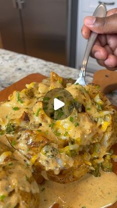 a person is holding a spoon over some food on a wooden plate with broccoli and cheese