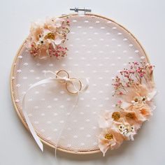 an embroidery hoop with flowers and two wedding rings