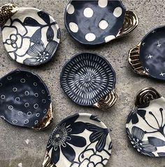 six black and white plates sitting on top of a cement floor next to each other