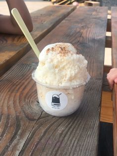 an ice cream sundae sits on a picnic table with two people sitting in the background