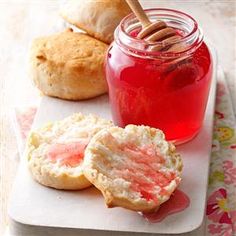 some cookies and jam on a tray with a wooden stick in the jar next to them