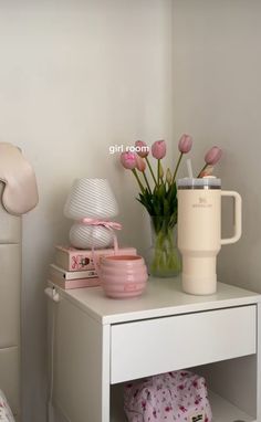 a white table topped with pink flowers next to a lamp and a vase filled with tulips