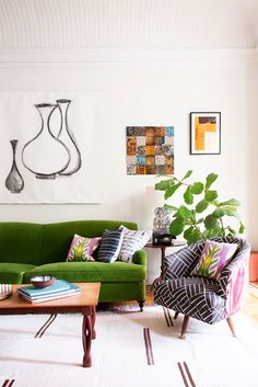 a living room with green couches and pictures on the wall above them, along with a coffee table