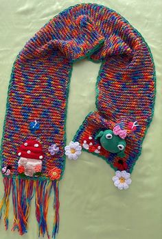 a knitted scarf with flowers on it and a small stuffed animal in the middle