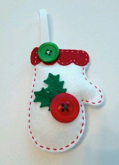 a felt ornament with buttons and holly leaves hanging from it's side