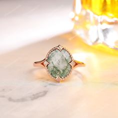 a green ring sitting on top of a table next to a glass bottle with liquid in it