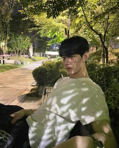 a young man sitting on a park bench at night