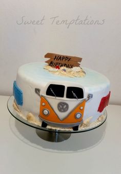 a birthday cake with an orange and white vw bus on the front is sitting on a table