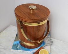 a wooden bucket sitting on top of a counter next to a lemon slice and spoon