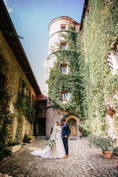 a bride and groom standing in front of an ivy covered building