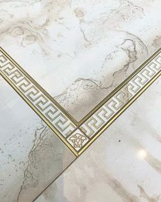 a white marble table with gold trimmings and greek designs on the top edge