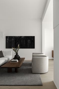 a modern living room with white walls and wood flooring, large painting on the wall