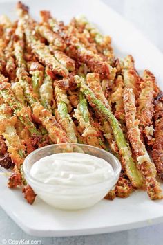 fried asparagus with ranch dressing on a white plate