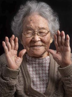 an elderly woman with hands up in front of her face