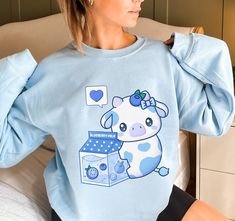 PLEASE NOTE:  This is a UNISEX sweater.  If you want an oversized look then consider ordering up a size. This cute blueberry milk cow sweater will look adorable on you!  Makes for a great kawaii gift for your loved ones as well. The collar is ribbed knit, so it retains its shape even after washing. There are no itchy side seams on these sweaters.  .: 50% cotton, 50% polyester .: Medium-heavy fabric (8.0 oz/yd² (271.25 g/m .: Loose fit .: Sewn-in label .: Runs true to size Blue Harajuku Cotton Sweatshirt, Blue Cotton Harajuku Sweatshirt, Blue Long Sleeve Kawaii Sweatshirt, Cute Blue Sweatshirt With Graphic Print, Cow Clothes, Blueberry Cow, Cow Sweater, Kawaii Cow, Blueberry Milk