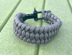 a close up of a bracelet on a green surface with a black metal object in the background