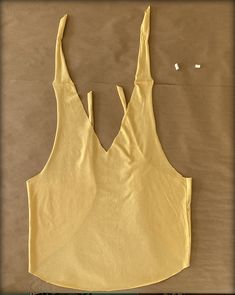 the back of a yellow tank top is cut out and placed on a brown surface