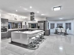 a large kitchen with stainless steel appliances and white counter tops, along with bar stools