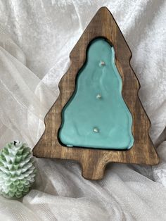 a small christmas tree shaped candle holder with a pine cone next to it on a white sheet