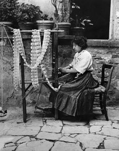 an old photo of a woman sitting in front of a table with beads on it