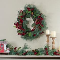 a christmas wreath and candles on a mantle