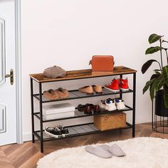 a shoe rack with several pairs of shoes on it in front of a door and potted plant