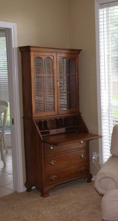 a living room with a chair, desk and china cabinet