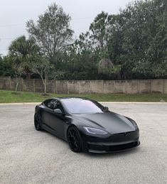 a black tesla parked in a parking lot