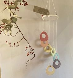 a mobile is hanging on the wall next to a branch with leaves and branches in it