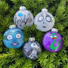 four painted christmas ornaments sitting on top of a tree