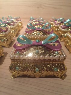 four gold and purple boxes with bows on them sitting on a wooden table next to each other