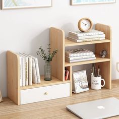 a desk with a laptop, bookshelf and various office supplies on top of it