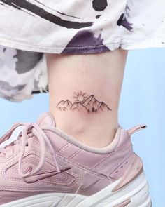 a woman's foot with a small mountain tattoo on her left side ribcage