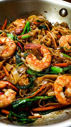 stir fried noodles with shrimp and vegetables in a pan