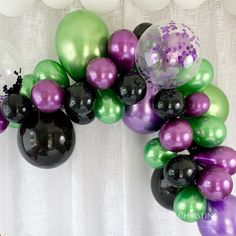 a bunch of balloons that are in the shape of an arch with purple, green and black balloons