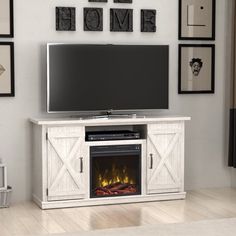 a white entertainment center with a fireplace in the middle and pictures on the wall above it